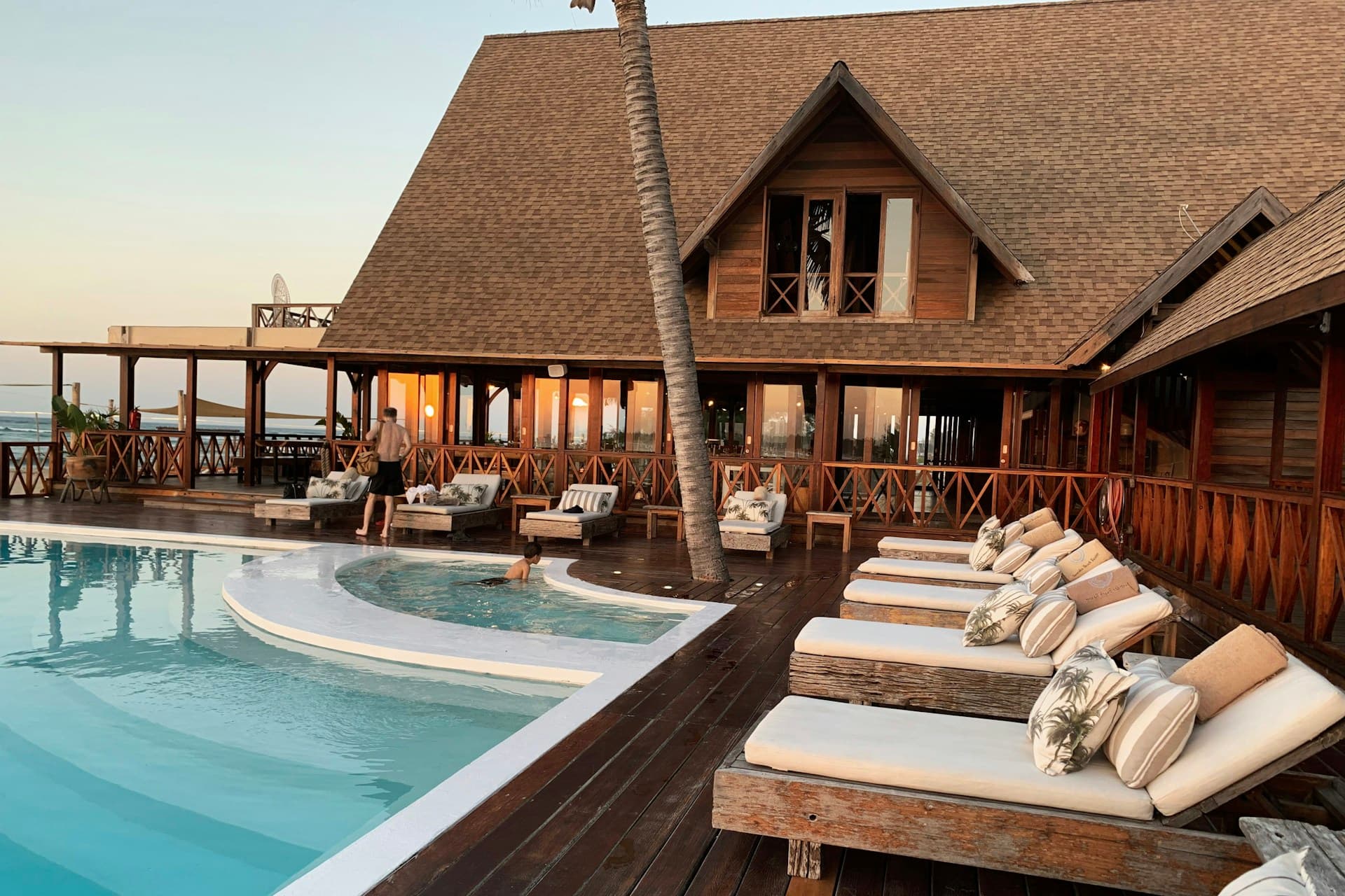 Luxury resort swimming pool at dusk with palm silhouettes and calm water